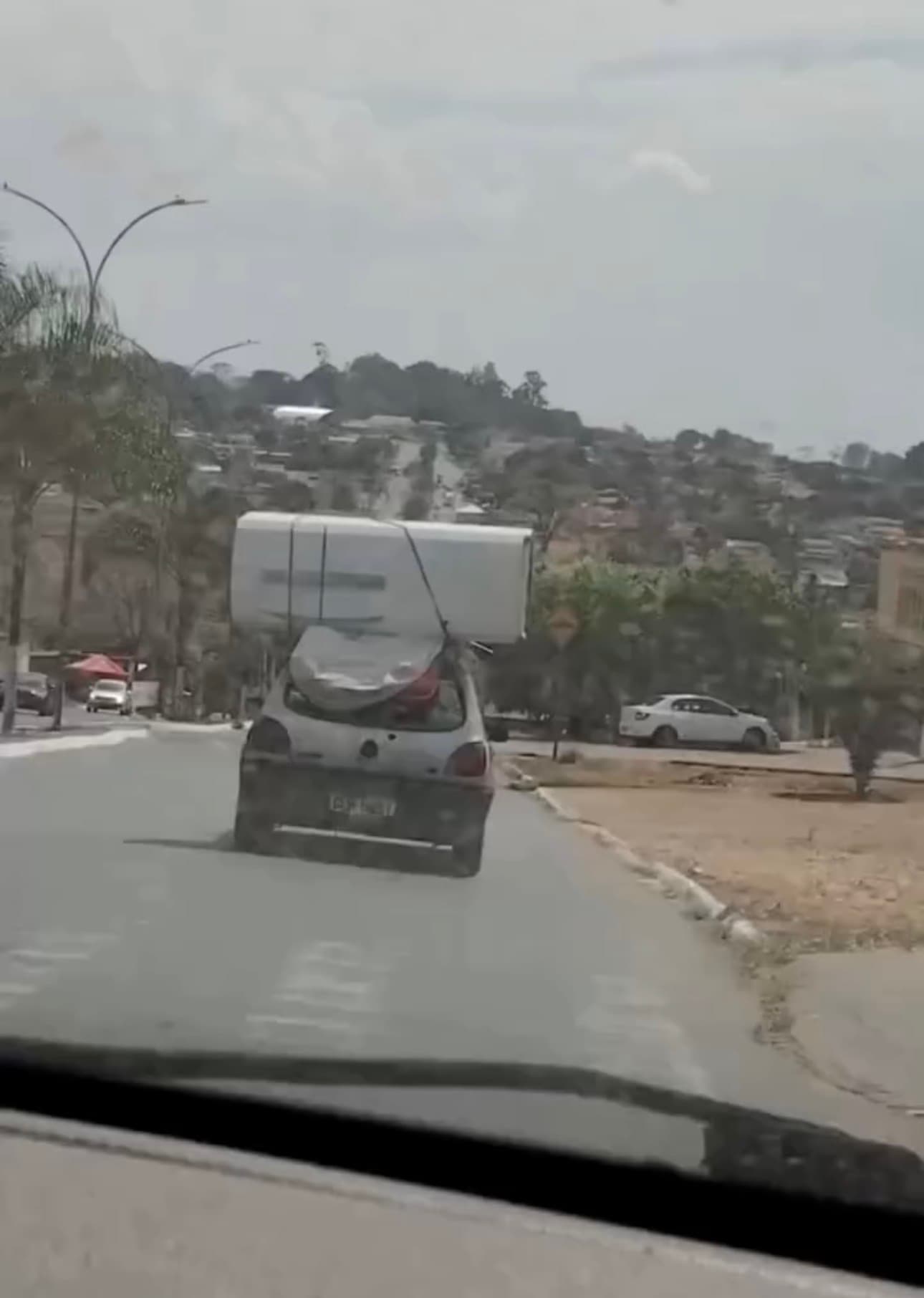 Carro tenta transportar geladeira no teto, carga cai na pista e quase provoca acidente em Trindade