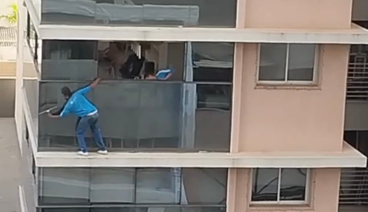 Flagrante mostra trabalhadores pendurados em janela de prédio para limpar vidraça